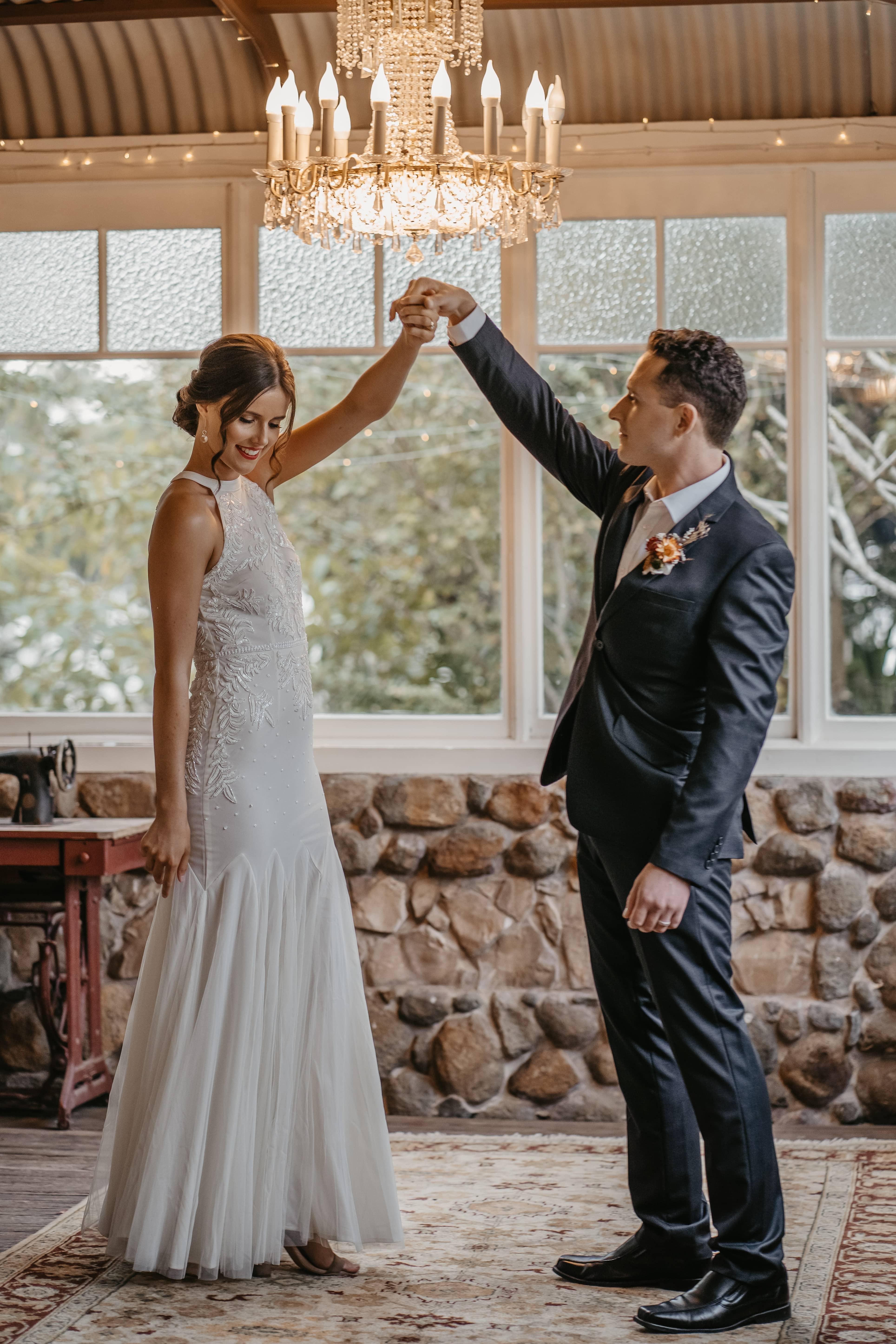 Bride and groom dancing in the corner of the historic stone conservatory under a large chandelier, PortStephens