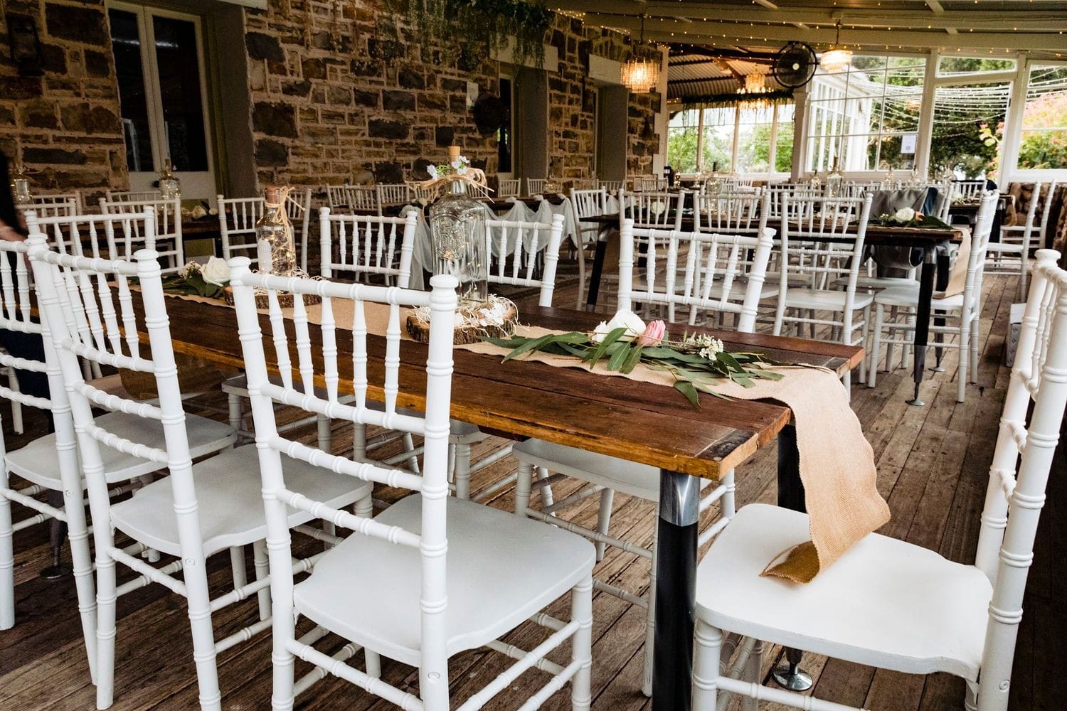 Large historic conservatory with stone walls set up for a wedding with rustic tables, chairs and styling at Tanilba House, Port Stephens