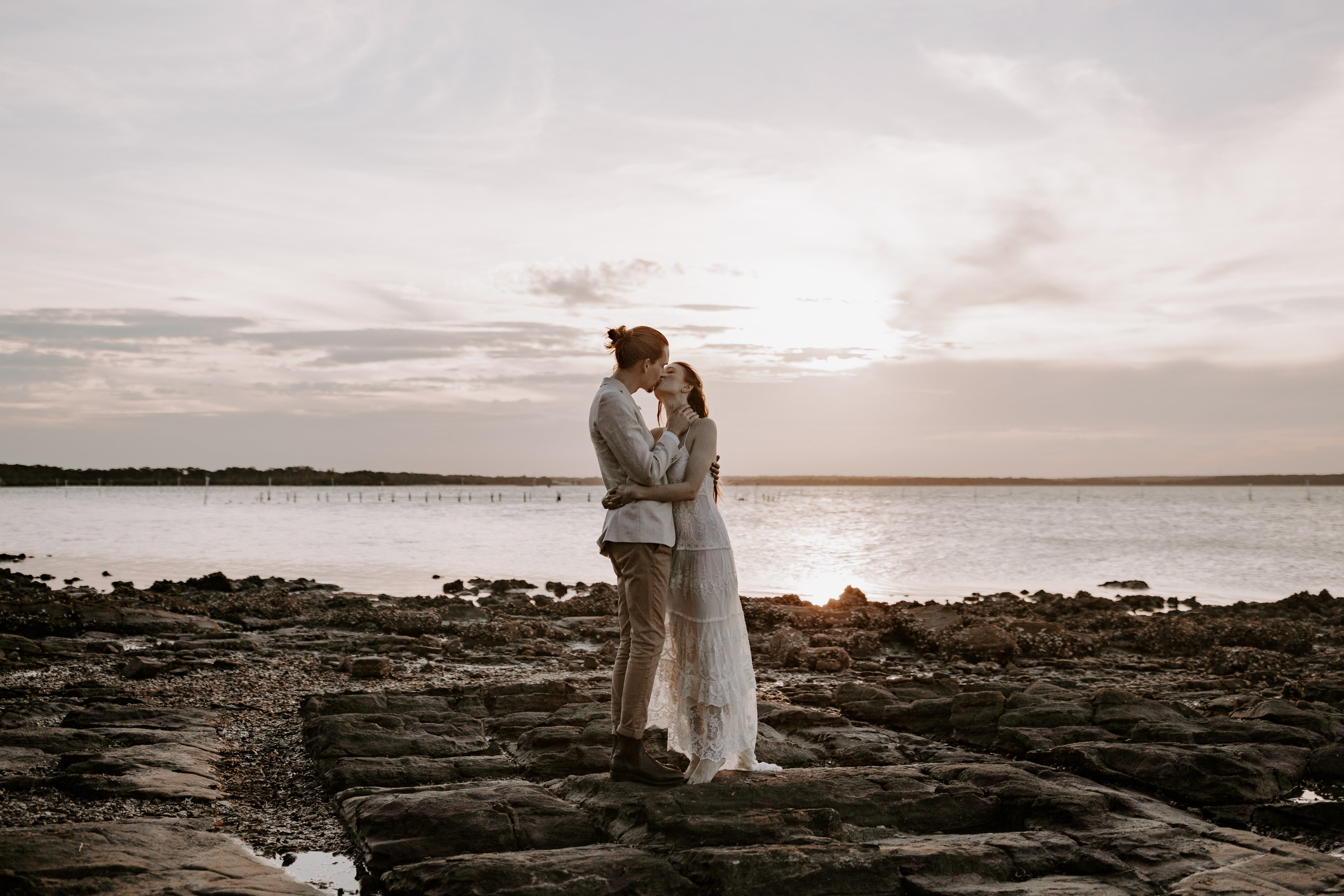 Wedding couple embracing on the rocks with Port Stephens and an overcast sky in the background