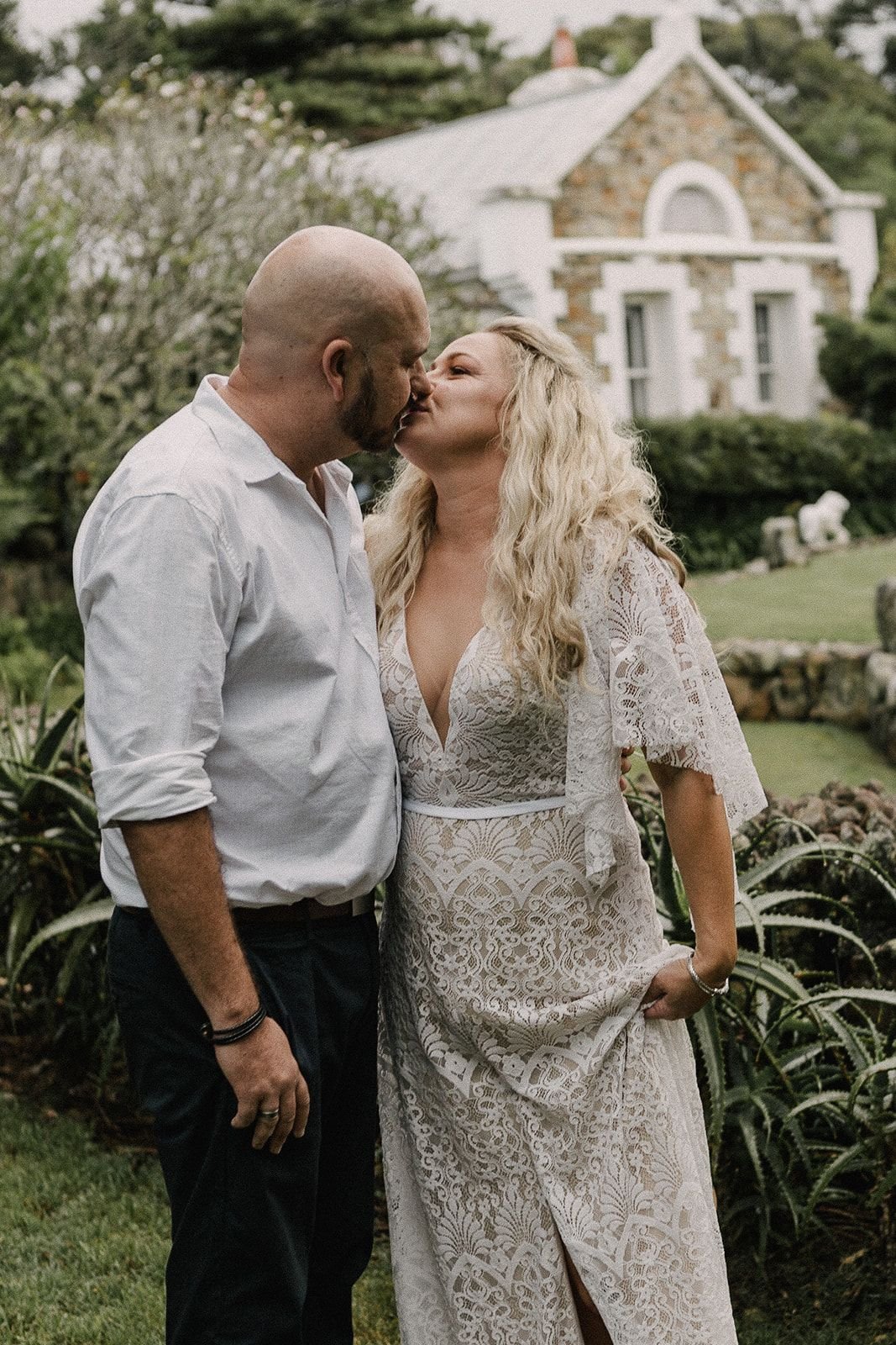 Wedding ceremony under 20m long garden arbour covered in vines with fairy lights & rustic styling. Wedding couple on rug with wedding guests looking on.