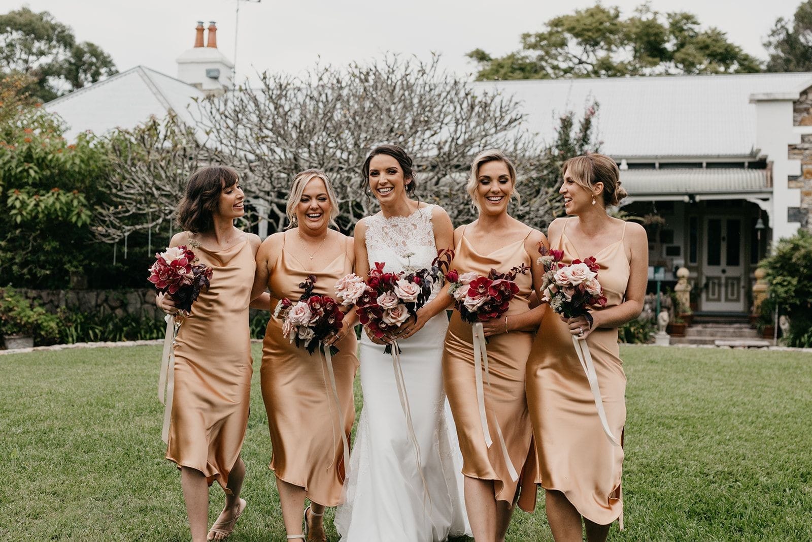 Bride with 4 bridesmaids in rust coloured dresses in front of historic colonial Tanilba House Port Stephens
