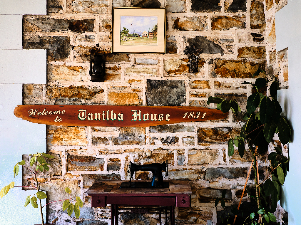 Tanilba House sign on verandah stone wall with vintage sewing machine. Tanilba House wedding venue Port Stephens